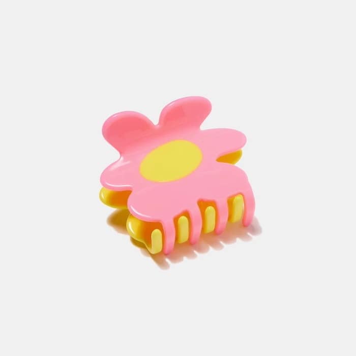 A perfect summer hair accessory, this pink and yellow claw clip is shaped like a flower with cheerful yellow petals and center, photographed on a plain white background.