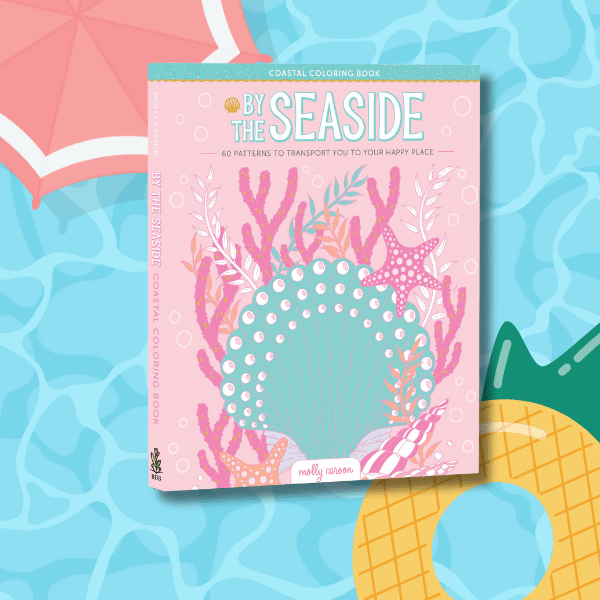 A pastel-colored By the Seaside coloring book, perfect for your TBR of tropical books, features seashell, coral, and seaweed artwork on the cover and is displayed on a pool-patterned background with a beach umbrella and pineapple-shaped pool float.
