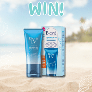 Blue tube and box of Bioré Aqua Rich UV sunscreen with SPF 50 on a sandy beach, surrounded by tropical elements, and the word WIN! in bold letters above the products.
