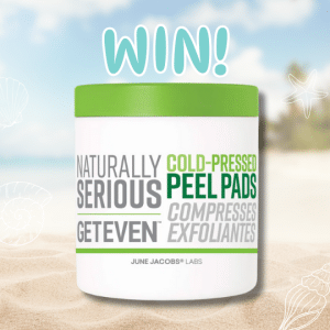 A container of Naturally Serious Exfoliating Pads sits on sand with WIN! written above it, against a blurred beach background with seashell illustrations.