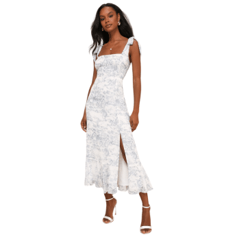 A woman wears a white and light blue floral sleeveless dress with shoulder tie straps, a square neckline, and a side slit—perfect summer fashion and ideal outfit inspiration for fans of The Summer I Turned Pretty outfits. She pairs it with white high-heeled sandals.