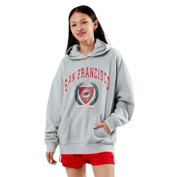 A young woman wearing a gray San Francisco hoodie with a crest design stands with one hand in the pocket and red shorts, facing the camera and smiling slightly—perfect summer fashion inspired by The Summer I Turned Pretty outfits.