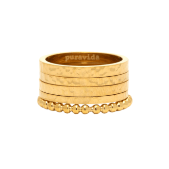 Four gold rings stacked together: three have a hammered texture, and one features a beaded design. The inner band is engraved with puravida. A chic addition to summer fashion and perfect for effortless outfits. White background.
